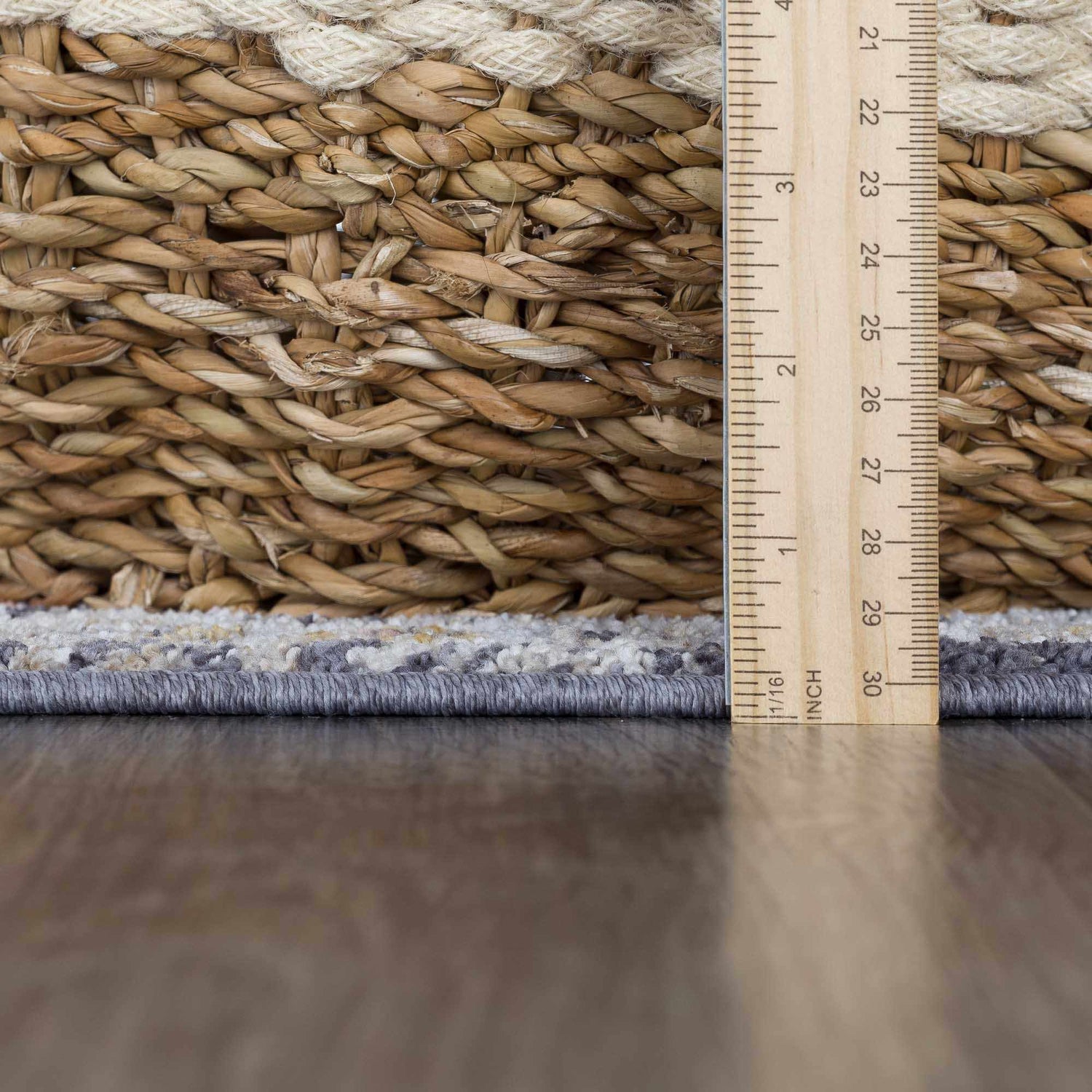 Close-up of Ivria Navy & Rust Area Rug showing light gray and natural gray tones with a ruler for scale. Woven texture detail. Pile