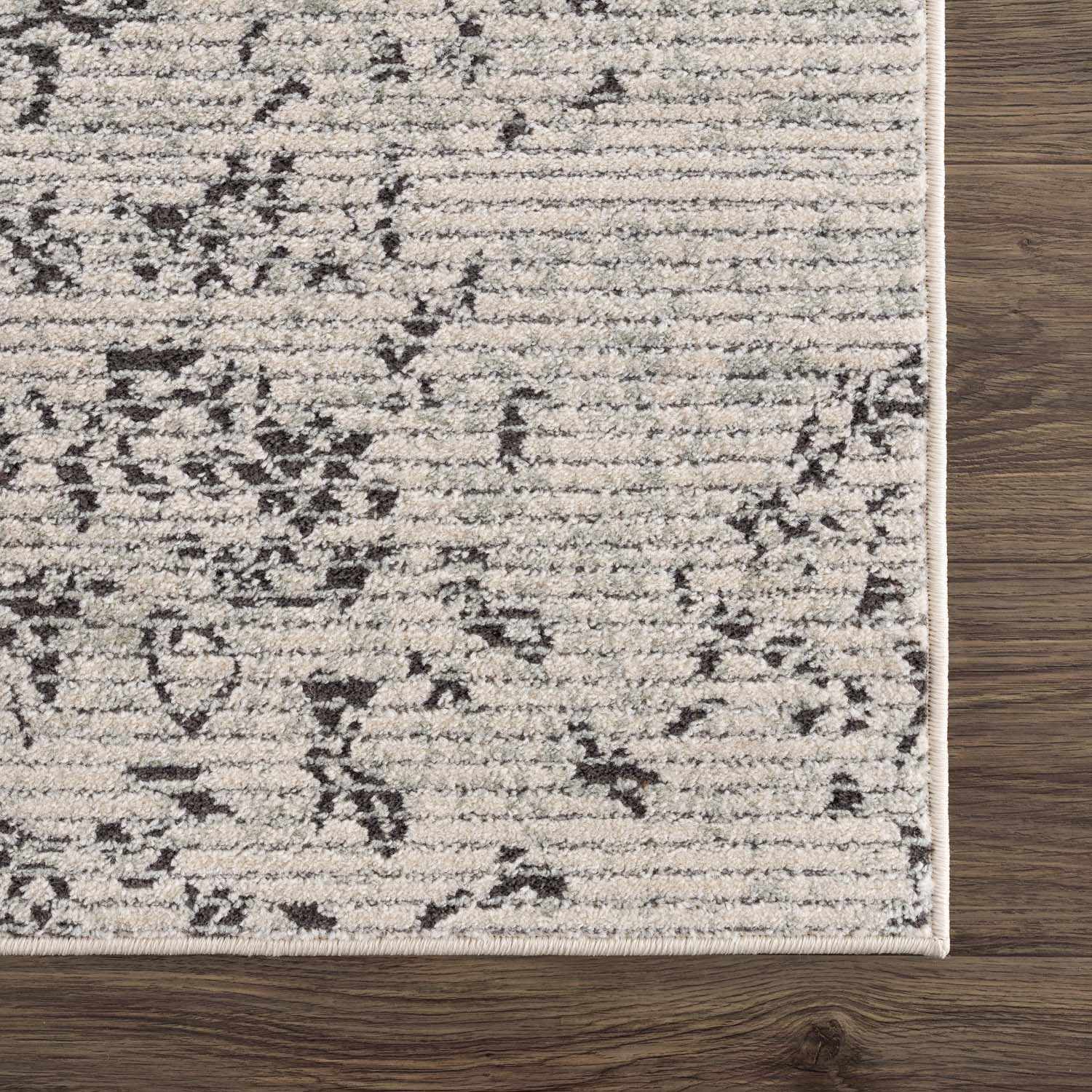 Close-up of the Paicines Area Rug. Charcoal and gray vintage pattern on light beige. Machine woven texture. Swatch