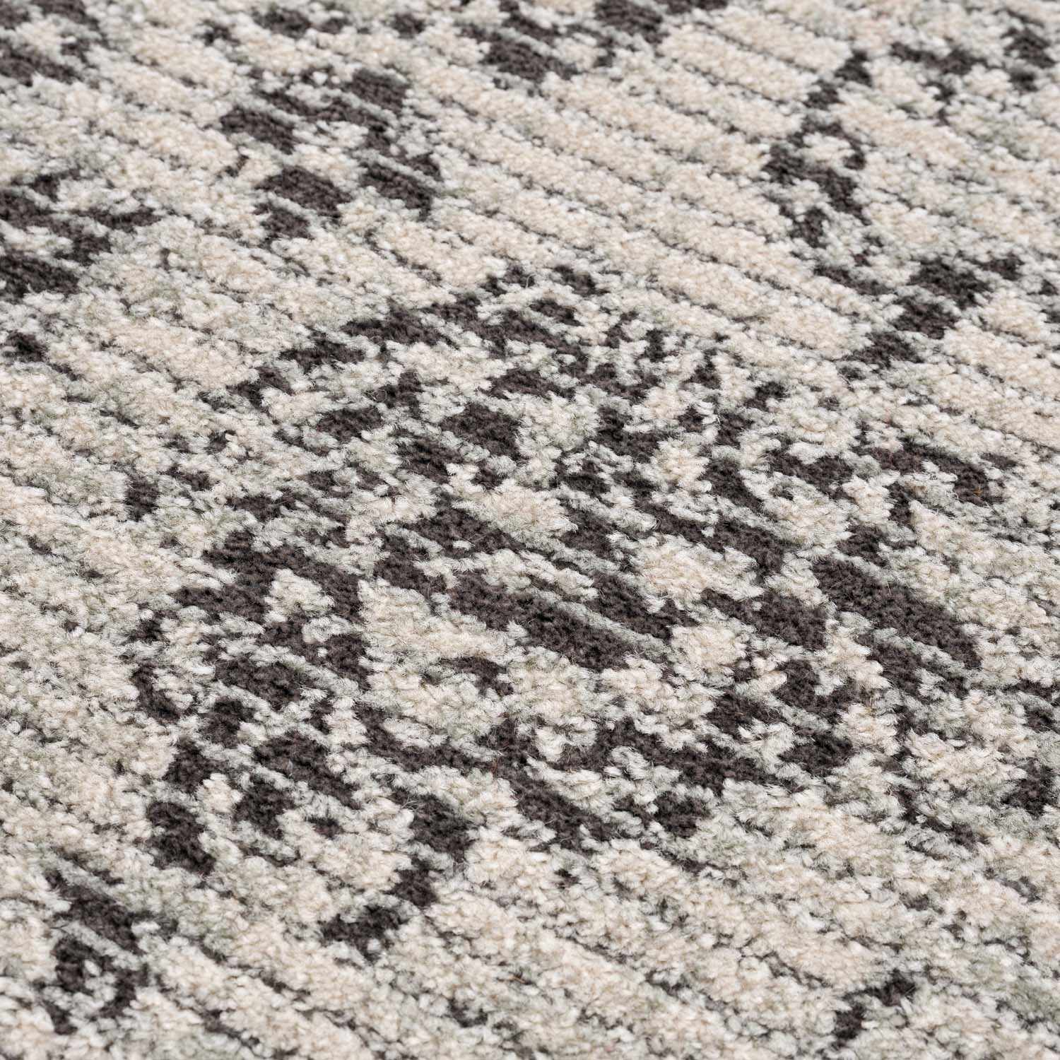 Close-up of the Paicines Area Rug, showcasing its charcoal and beige vintage-style pattern and textured, machine-woven construction. Texture