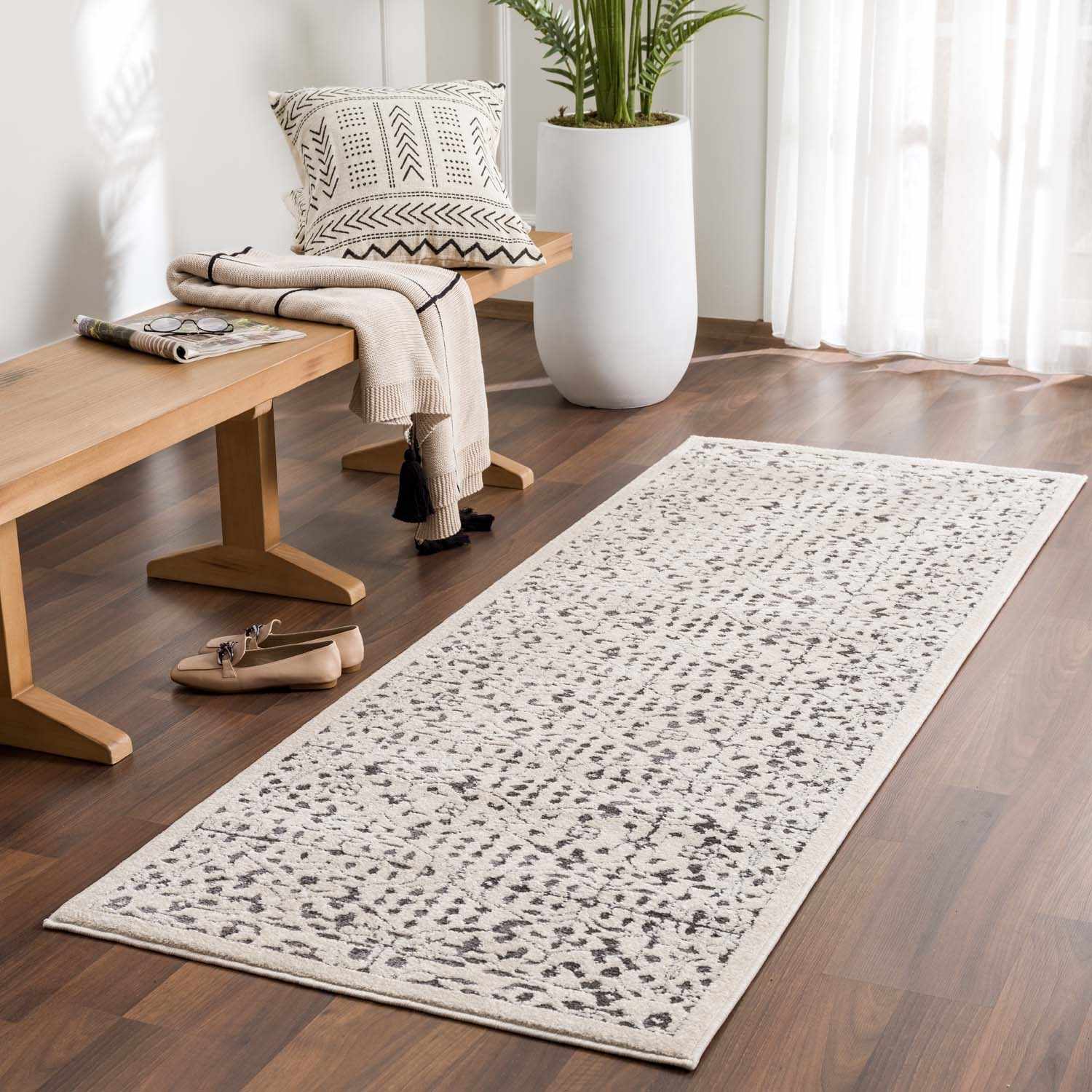 Entryway with Sattley Area Rug in beige and charcoal, wood bench, patterned pillow, and tan shoes. Roomscene-Runner