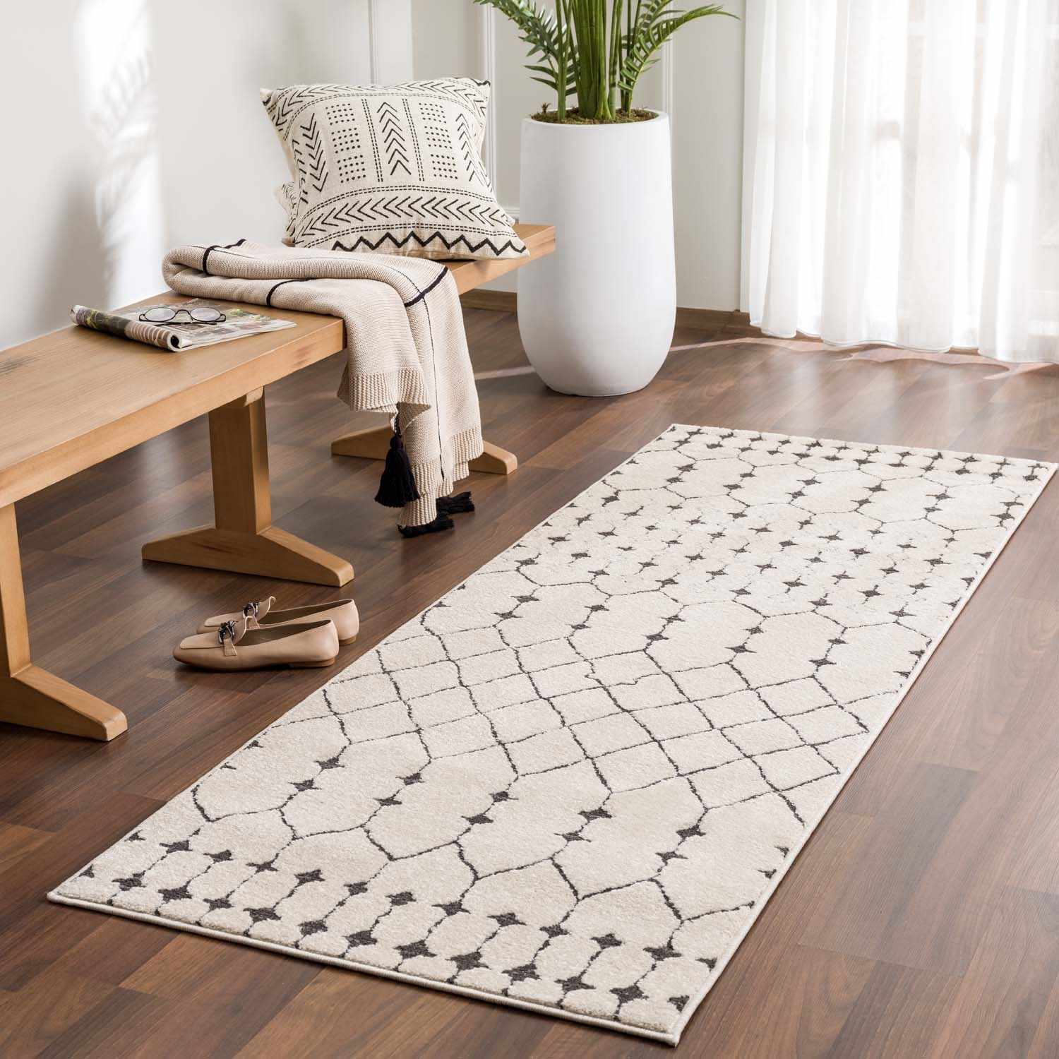 Entryway with a Chubbuck Moroccan Trellis Rug in light beige and charcoal, bench, decorative pillow, and wood floors. Roomscene-Runner