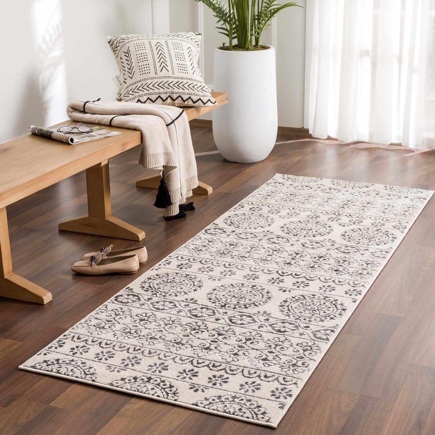 Entryway scene with a Warroad Area Rug runner in light beige and charcoal, wood bench, and potted plant. Roomscene-Runner