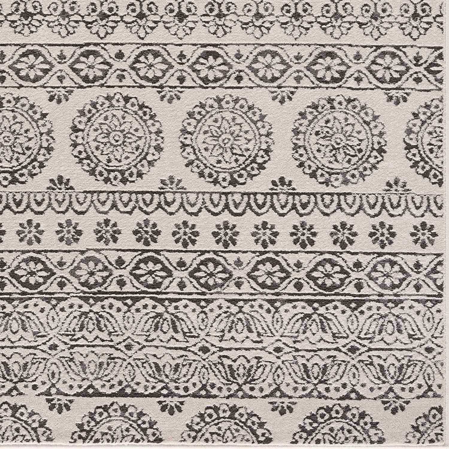 Close-up of the Warroad Area Rug. Charcoal and light beige rug with a traditional, floral-inspired pattern. Swatch