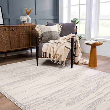 Cozy living room scene with a bone Lave Bone Area Rug, gray chair, wood cabinet, and natural light. Roomscene-Rectangle