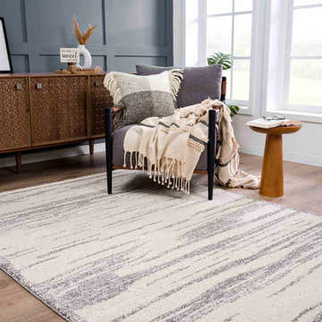 Living room scene with Lave Bone & Taupe Area Rug, gray accent chair, wood cabinet, and neutral decor. Roomscene-Rectangle