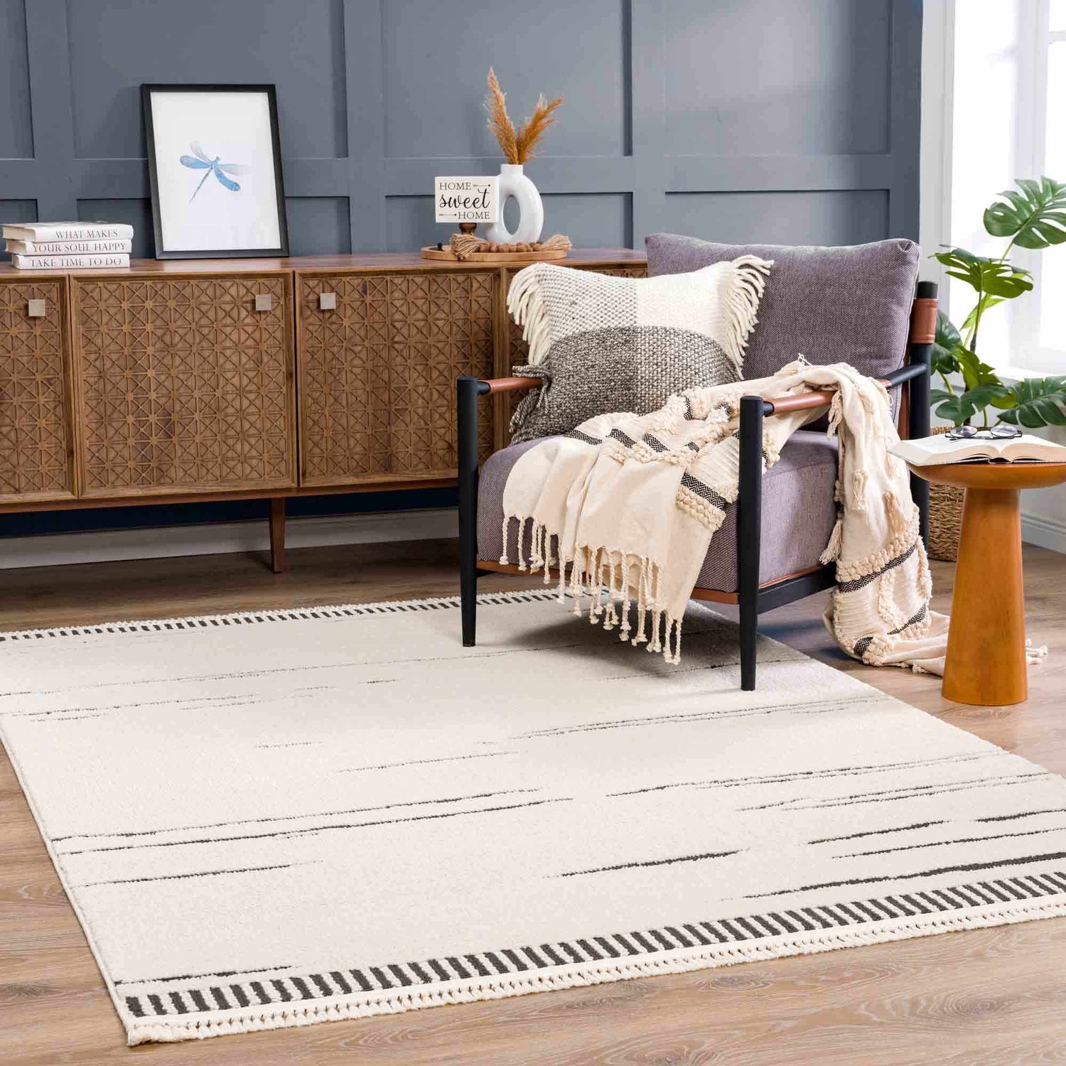 Living room scene with bone Aulii Area Rug, gray chair, wood cabinet, and blue accent wall. Roomscene-Rectangle