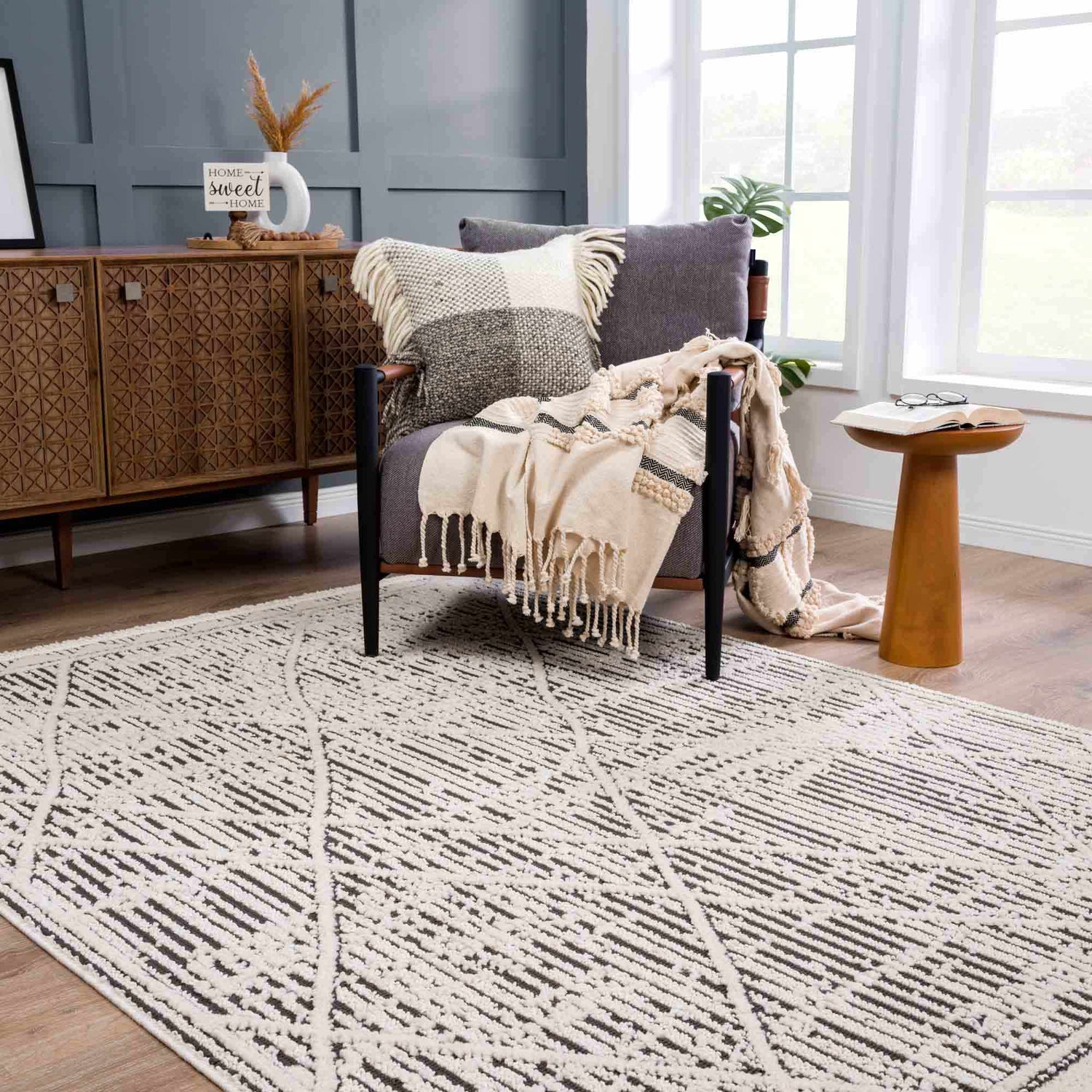 Living room scene with a beige Umay Textured rug, gray chair, and wood cabinet. Neutral tones create a cozy, Scandinavian vibe. Roomscene-Rectangle