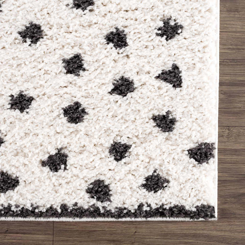 Close-up of the plush Chaia Dotted Black & White Rug showing its soft texture and dotted pattern on a wood floor. Swatch