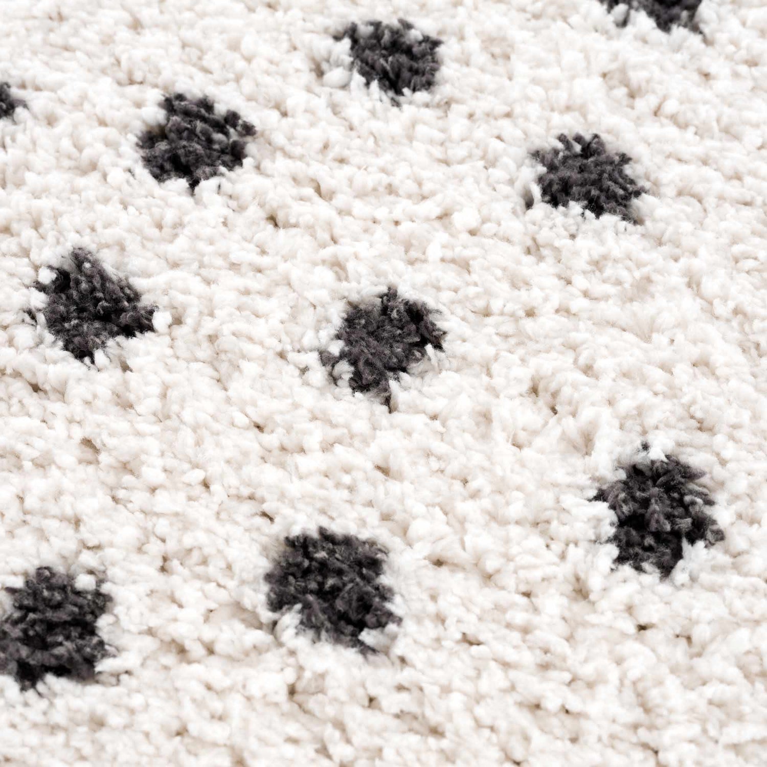 Close-up of the Chaia Dotted Black & White Plush Rug, showing its soft, shag texture and black polka dot pattern. Texture