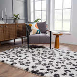 Living room scene with gray chair on Zhen Black Spots Leopard Rug, wood cabinet, and natural light. Roomscene-Rectangle
