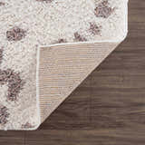 Close up of the Zhen Pink Spots Leopard Rug showing its shag texture and backing. Fold