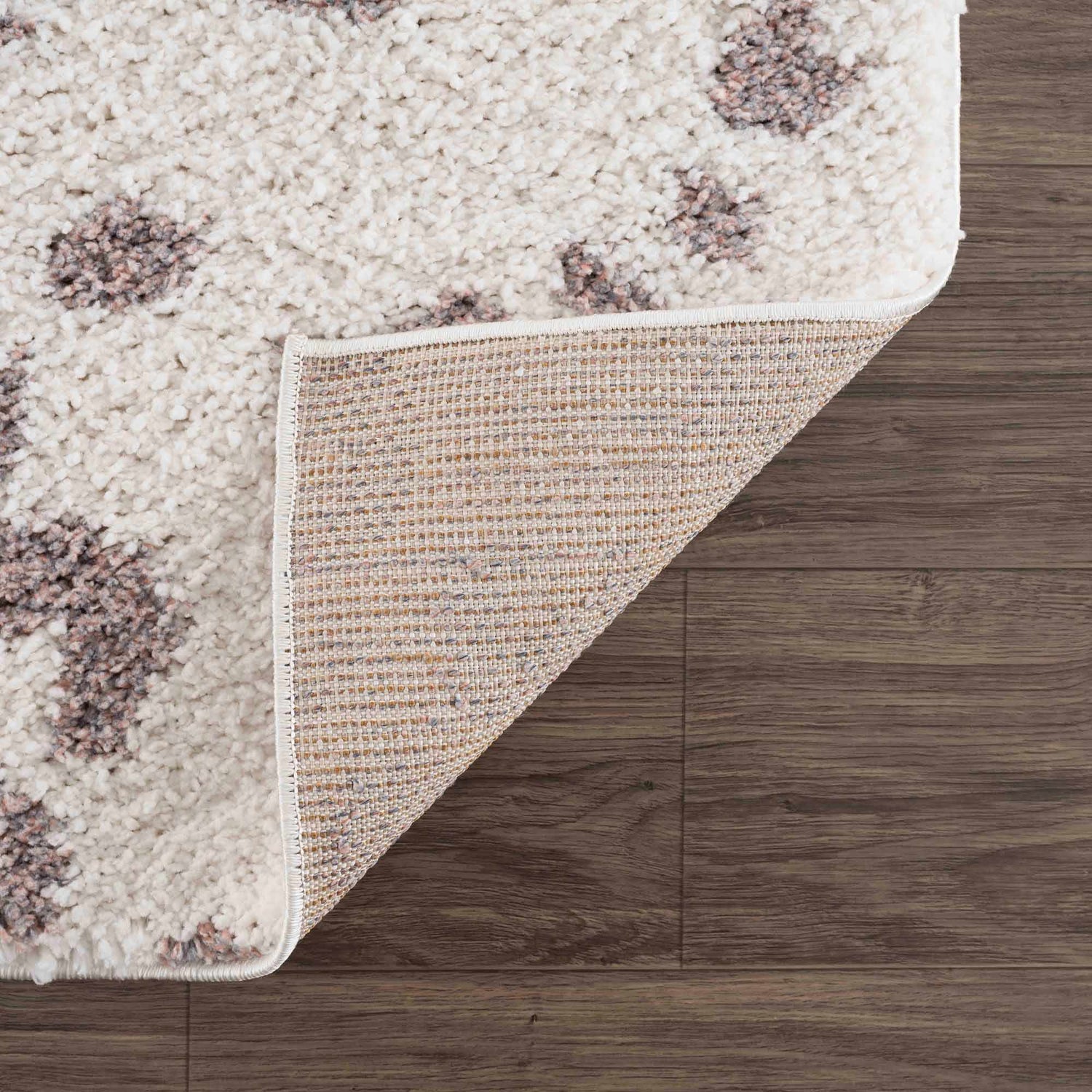 Close up of the Zhen Pink Spots Leopard Rug showing its shag texture and backing. Fold