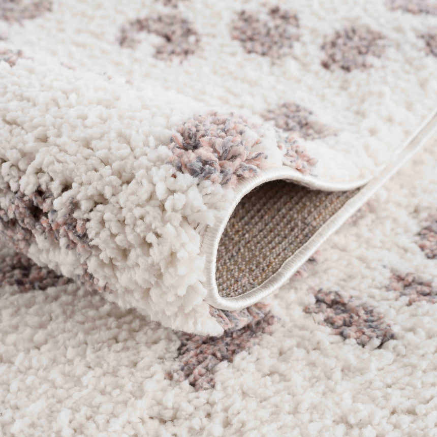 Close-up of the Zhen Pink Spots Leopard Rug, showing its shag texture and pink, brown, and off-white leopard spot design. Fold