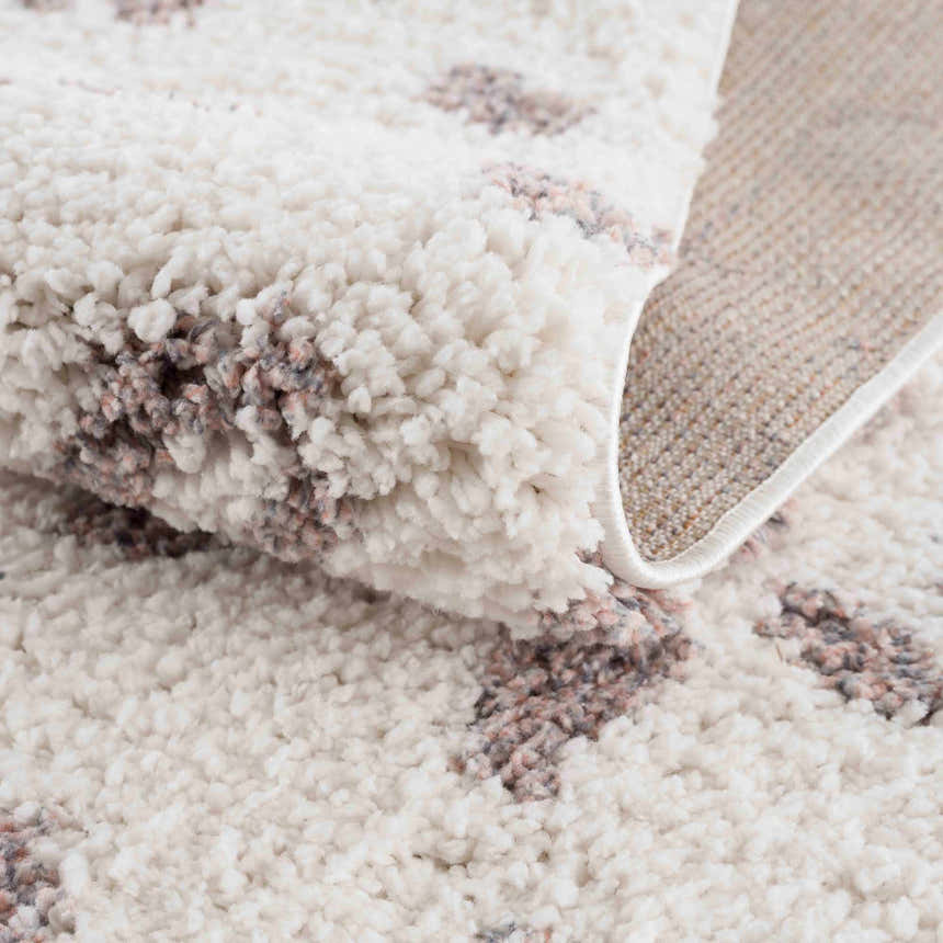 Close-up of the Zhen Pink Spots Leopard Rug showing the shag texture and pink and brown spots on an off-white background. Fold