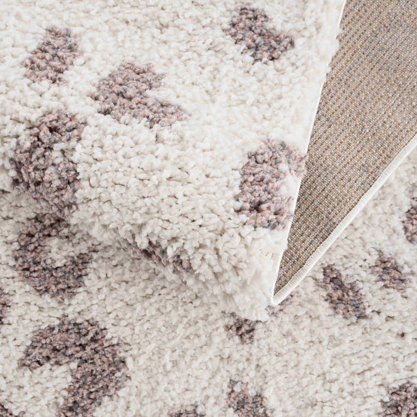 Close-up of the Zhen Pink Spots Leopard Rug, showing its shag texture, off-white base, and pink and brown leopard spots. Fold