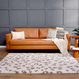 Living room scene with a brown leather sofa and the Zhen Pink Spots Leopard Rug. Roomscene-Rectangle