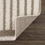 Close up of the Jola Beige Area Rug showing its beige and white stripes, shag texture, and backing on dark wood floor. Fold