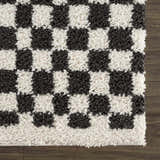 Close-up of the Kieu Black & White Checkered Shag Rug. Features a charcoal and off-white checkered pattern and shag texture. Swatch