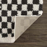 Close-up of the Kieu Black & White Checkered Shag Rug showing its fluffy texture and geometric checkered pattern. Fold
