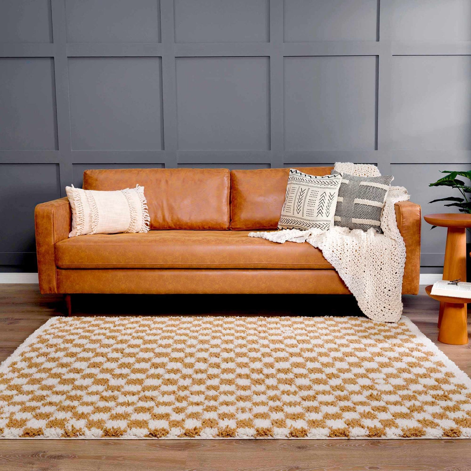 Living room scene with a Kieu Mustard & Ivory Checkered Area Rug, brown leather sofa, and gray accent wall. Roomscene-Rectangle