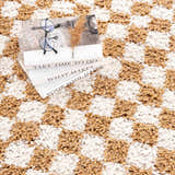 Close-up of the Kieu Mustard & Ivory Checkered Area Rug, a shag rug with a geometric checkerboard pattern. Styleshot