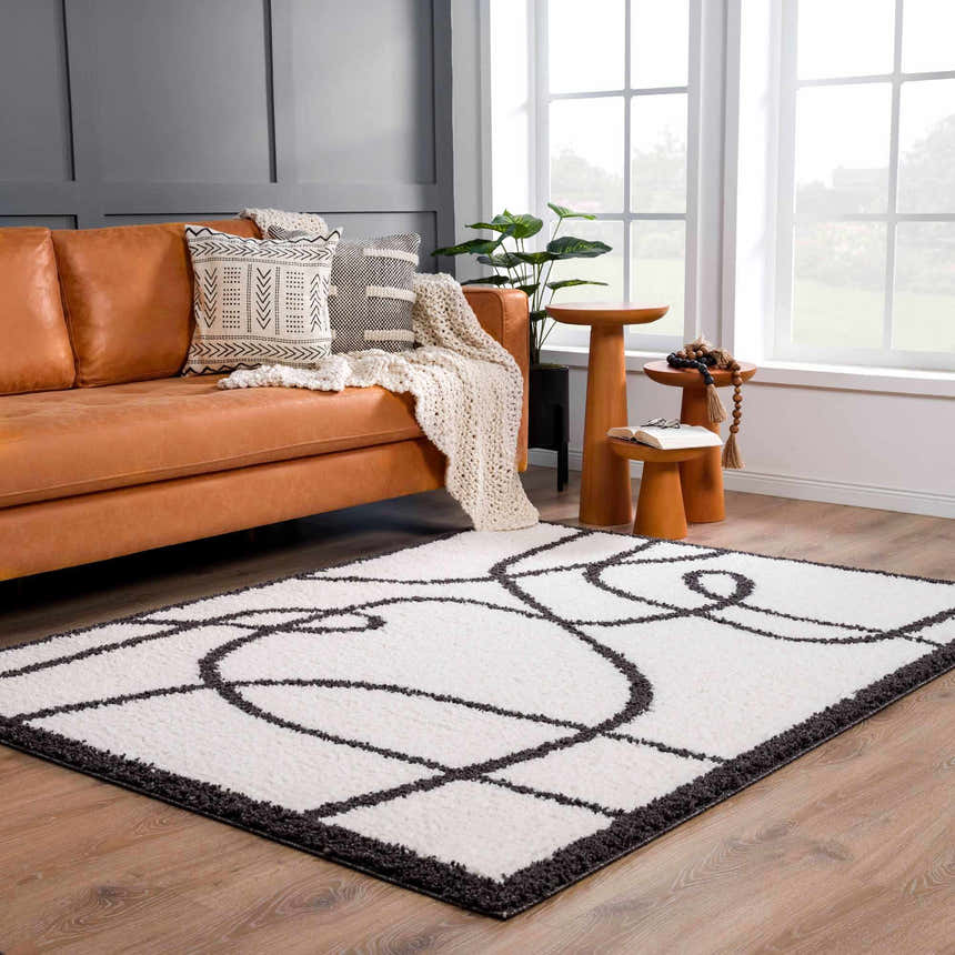 Living room scene with a Brad Area Rug, tan leather sofa, wood side tables, and neutral decor. Roomscene-Rectangle
