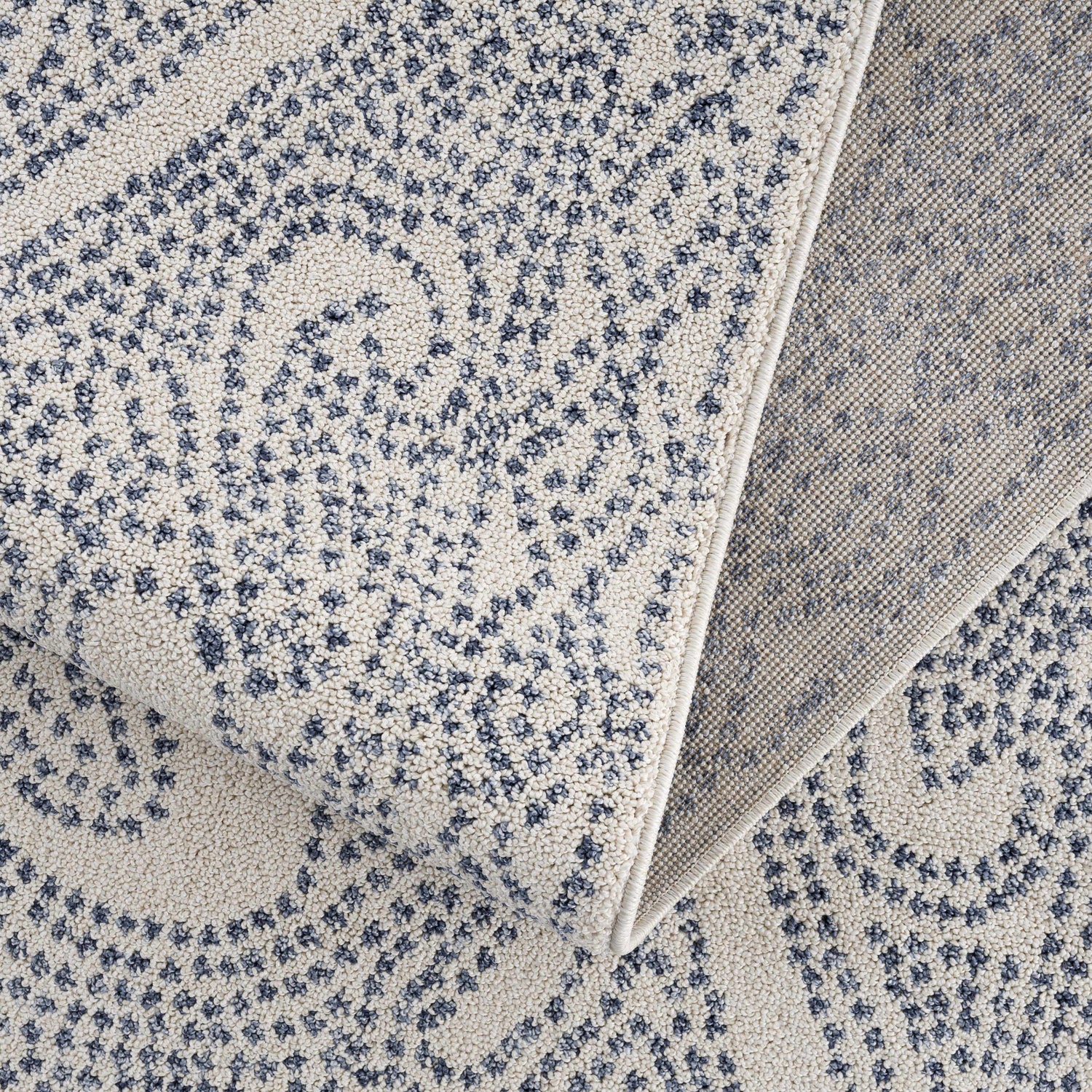 Close-up of the Birdwood Navy Area Rug showing its cream and dark blue bohemian pattern and machine-woven texture. Fold