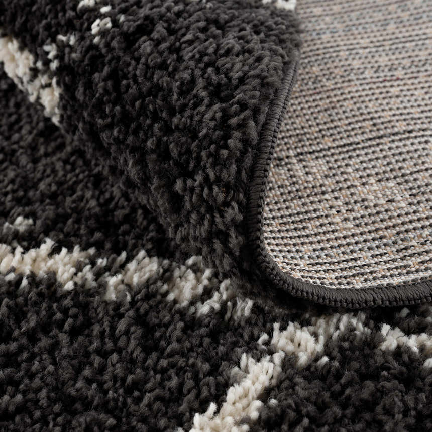 Close-up of the Wallagrass Black Moroccan Shag Rug, showing its charcoal and light beige colors and soft, textured shag pile. Fold