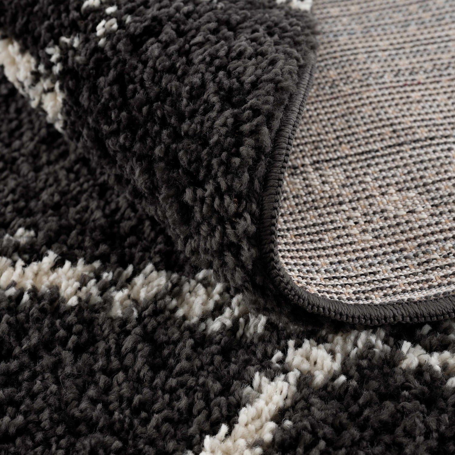 Close-up of the Wallagrass Black Moroccan Shag Rug, showing its charcoal and light beige colors and soft, textured shag pile. Fold