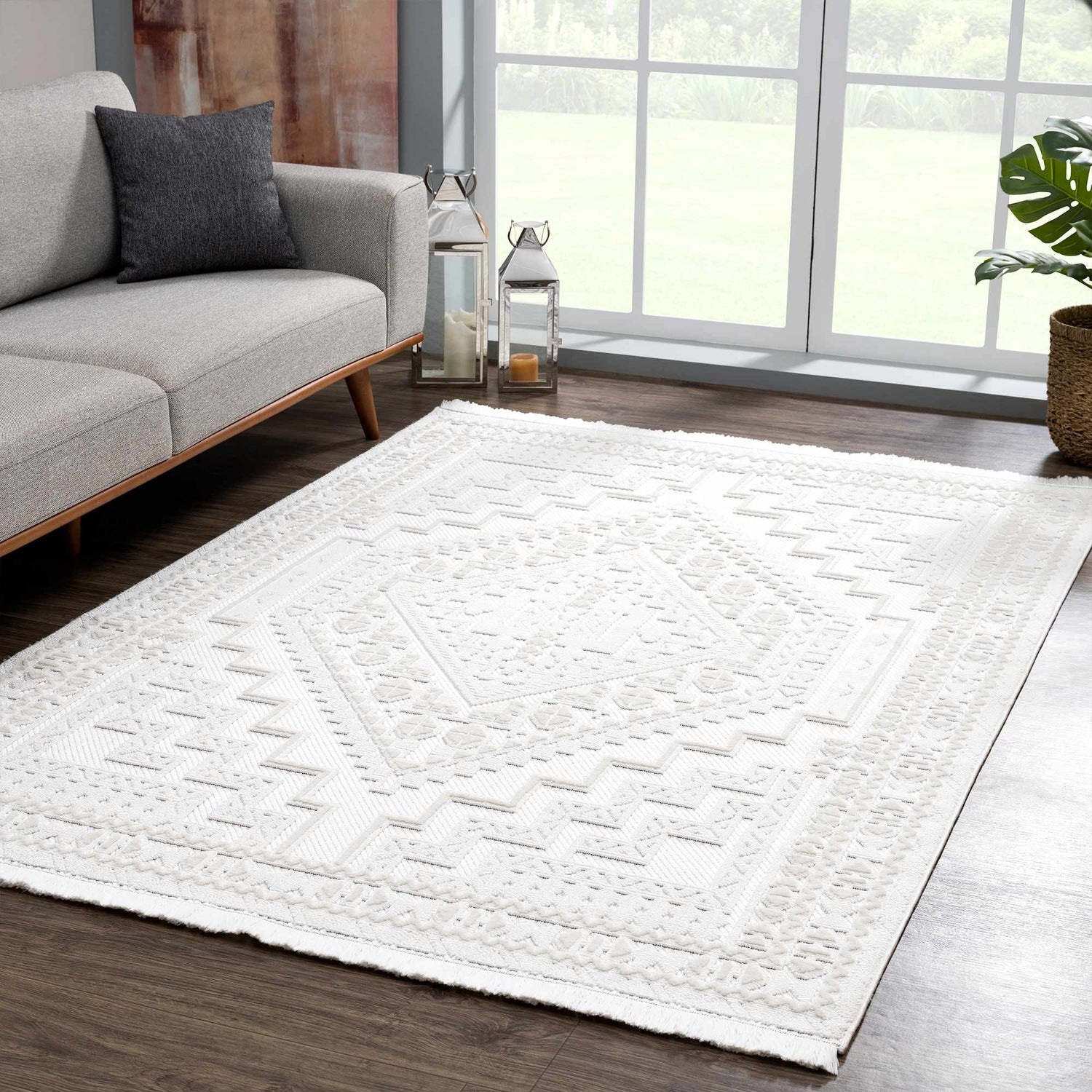 Living room scene with a gray sofa and Ivory Alya 3D Medallion Fringe Area Rug on a dark wood floor. Roomscene-Rectangle