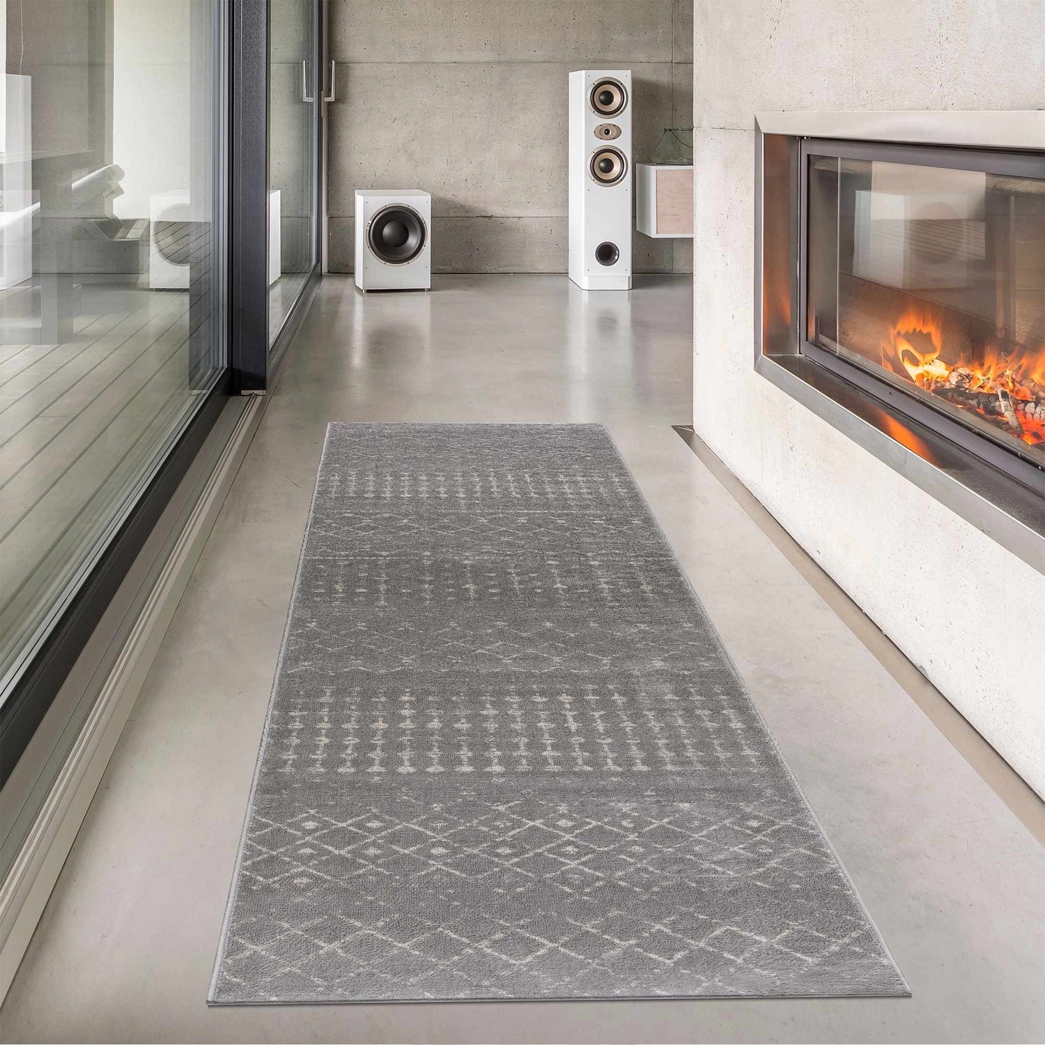 Modern hallway with gray Tigrican Gray 2330 Area Rug, fireplace, and speakers against a concrete wall. Roomscene-Runner