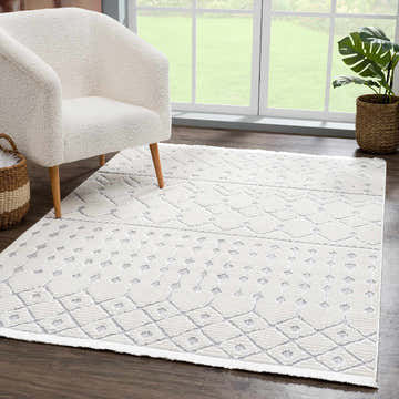 Living room scene with Ivory Gray Beil Textured Trellis Fringe Area Rug, white sherpa chair, and plant. Roomscene-Rectangle