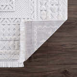 Close-up of Ivory Alya 3D Medallion Fringe Area Rug showing texture, fringe detail and backing on dark wood floor. Fold