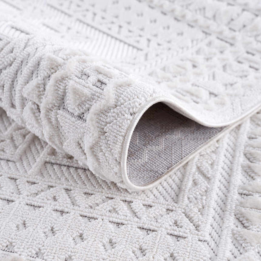 Close-up of the Ivory Alya 3D Medallion Fringe Area Rug showing the textured, geometric pattern and soft white color. Fold