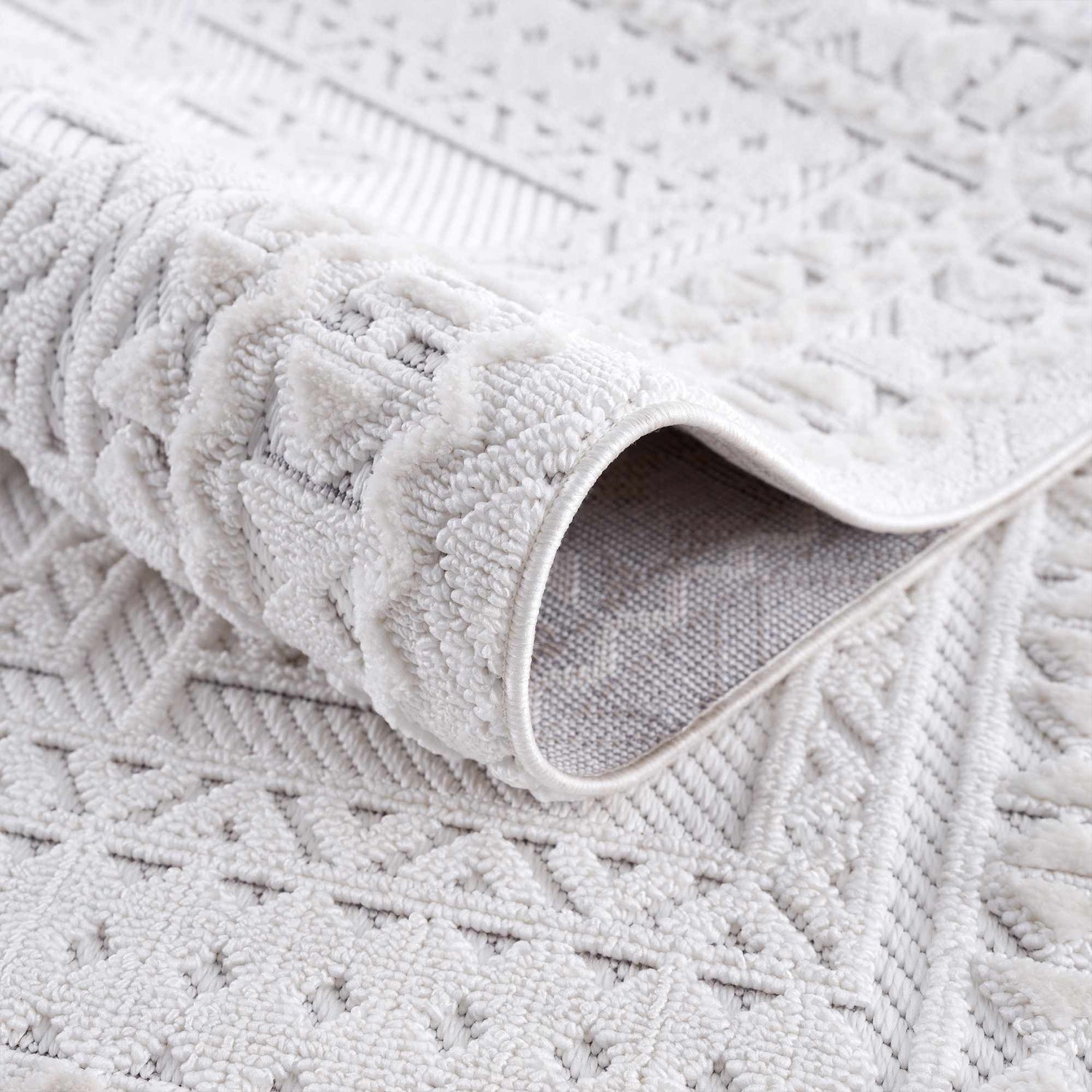 Close-up of the Ivory Alya 3D Medallion Fringe Area Rug showing the textured, geometric pattern and soft white color. Fold