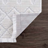 Close up of Ivory Beil 3D Fringe Area Rug showing geometric design, fringe detail, and rug backing on dark wood floor. Fold
