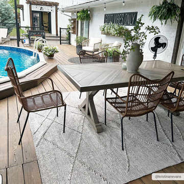 Outdoor dining area with Baqer Bone & Tan rug under a wood table and wicker chairs, poolside patio. Roomscene-Rectangle