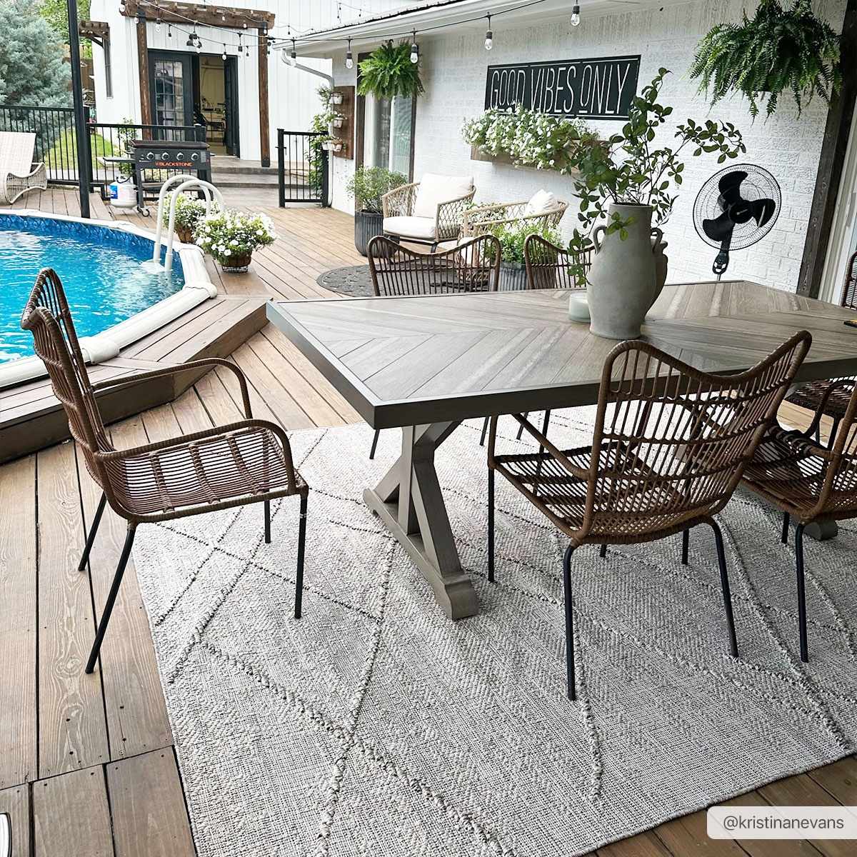 Outdoor dining area with Baqer Bone & Tan rug under a wood table and wicker chairs, poolside patio. Roomscene-Rectangle