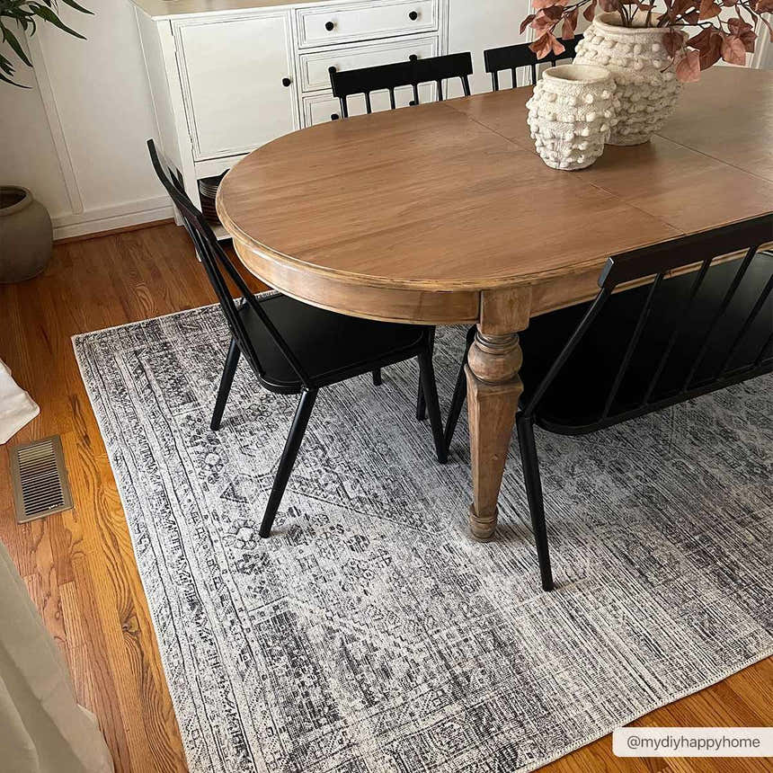 Dining room scene with a Barny Gray Blue Washable Rug under a wood table and black chairs. Farmhouse style. Roomscene-Rectangle