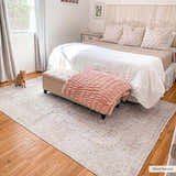 Bedroom scene with a beige Bethany Vintage Flat Pile Washable Rug, bed, bench, and orange cat on wood floor. Roomscene-Rectangle