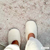 Close-up of a Bethany Vintage Flat Pile Washable Rug with beige, blush, and brown tones, paired with cozy white slippers. Styleshot