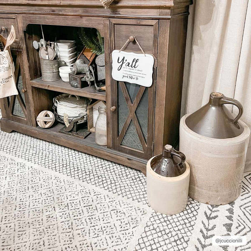 Farmhouse living room scene with a Burdette Soft Neutral Rug, dark wood cabinet, and neutral decor. Styleshot