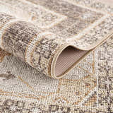 Close-up of the Albas Washable Area Rug showing its traditional vintage pattern and texture in light brown and dark brown tones. Fold