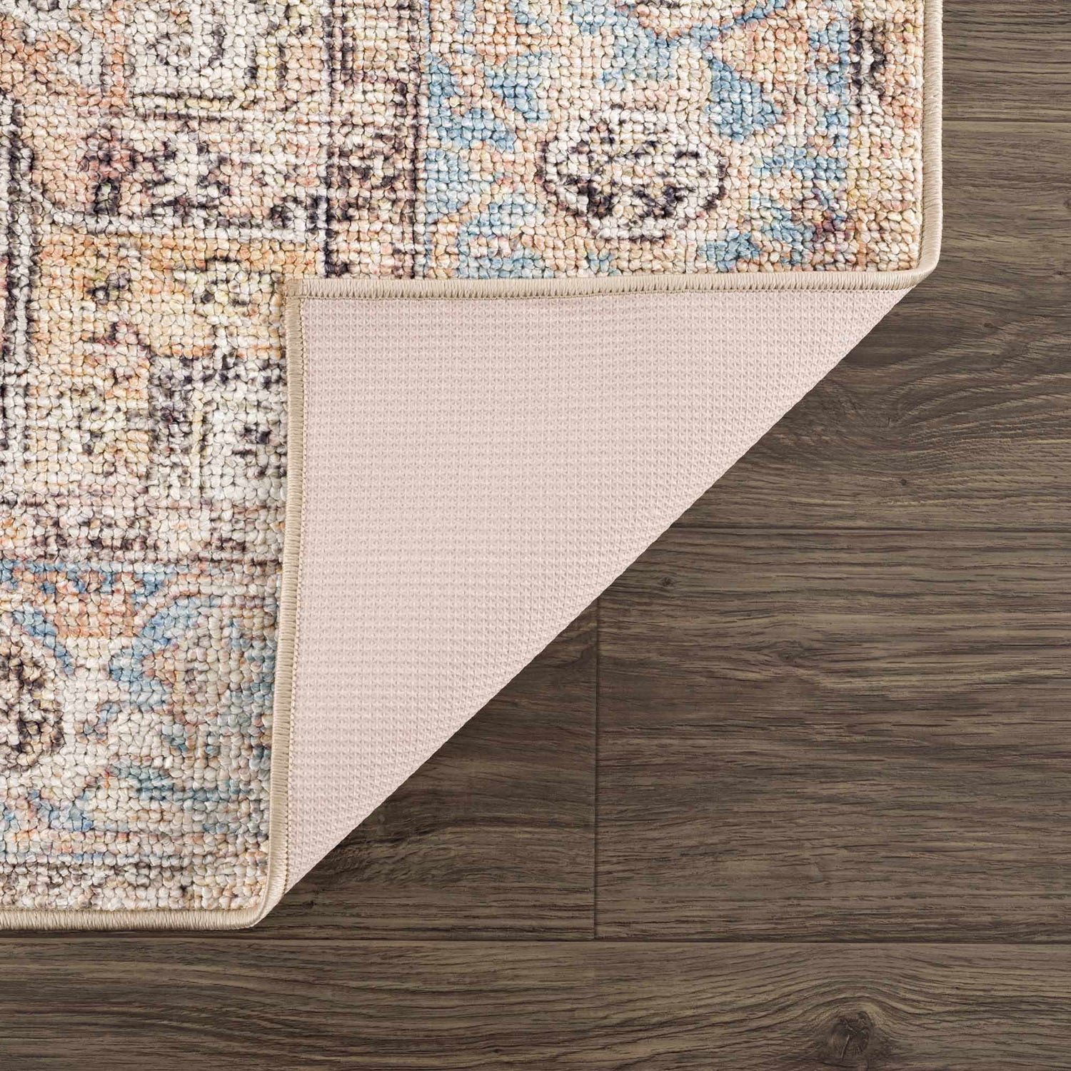 Close-up of Beck Peach Washable Area Rug showing oriental pattern, beige, blue, and peach tones, and non-slip backing. Fold