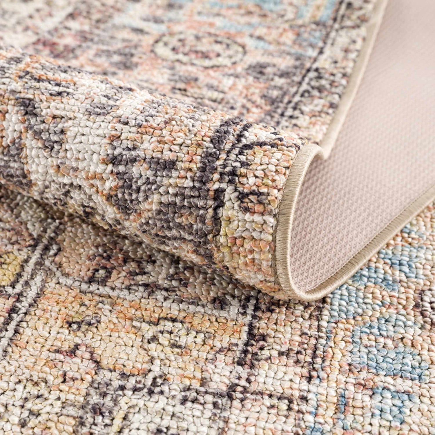 Close-up of Beck Peach Washable Area Rug showing beige, blue, and brown oriental pattern and textured, machine-woven construction. Fold