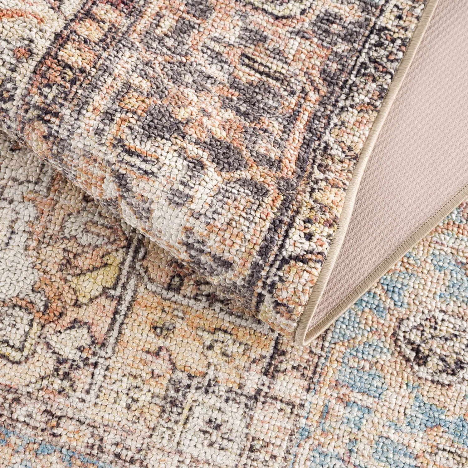 Close-up of the Beck Peach Washable Area Rug showing its traditional pattern, peach, beige, blue, and brown colors. Fold