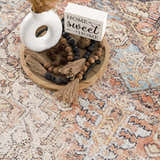 Close-up of Beck Peach Washable Area Rug, with beige, peach, and blue tones. Farmhouse style rug with a traditional pattern. Styleshot