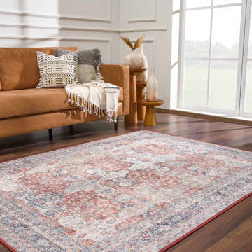 Living room scene with a brown couch and the Ambre Washable Area Rug in beige, blue, and burgundy. Roomscene-Rectangle