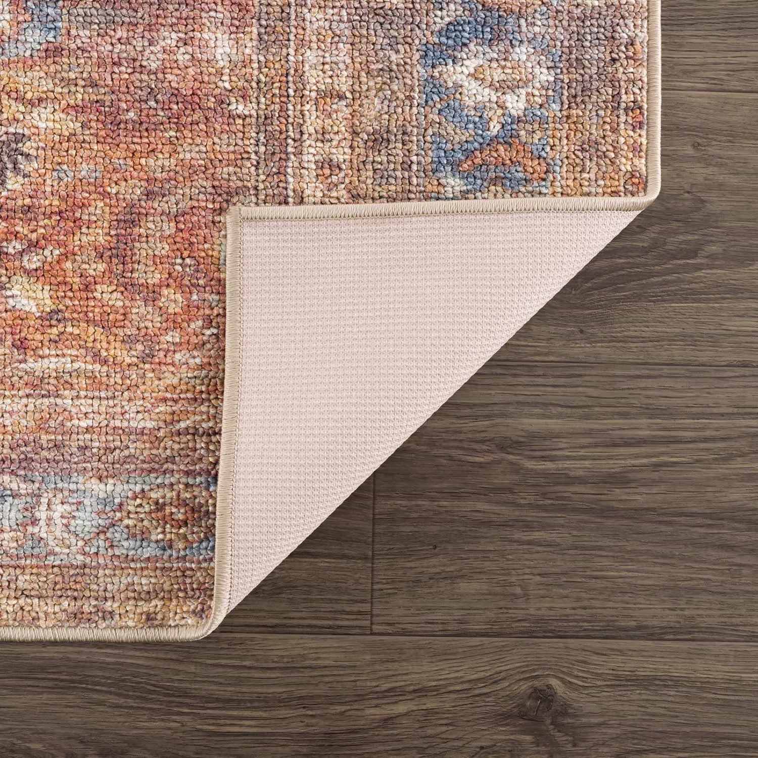 Close-up of Anshu Peach Washable Area Rug showing traditional vintage design, beige backing, and peach, blue, burgundy colors. Fold