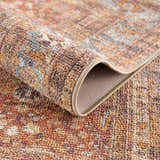 Close-up of the Anshu Peach Washable Area Rug showing its traditional vintage pattern, beige, blue, and burgundy colors. Fold